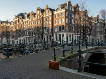 Amsterdam canal street with bicycles and luggage near canal houses