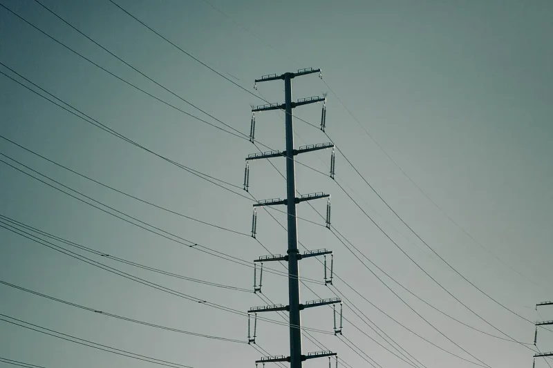 A line of high-voltage electricity pylons silhouetted against an evening sky