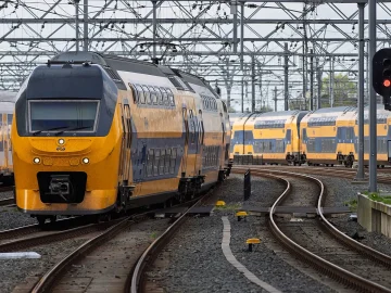 Yellow and blue NS intercity trains standing still at a Dutch railway yard beside a red signal